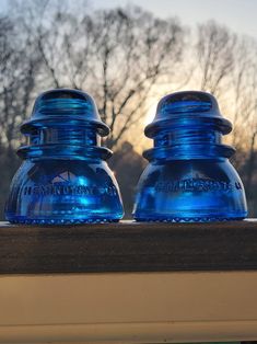 two blue water bottles sitting on top of a window sill next to each other