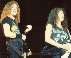 two women with long hair are standing on stage and one is holding an electric guitar