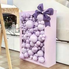 there is a large box with balloons in the shape of a bow on display at an event