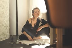 a woman sitting on the floor in front of a mirror with her eyes closed and holding a pencil