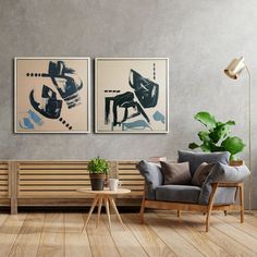 two paintings hang on the wall next to a couch and coffee table in a living room