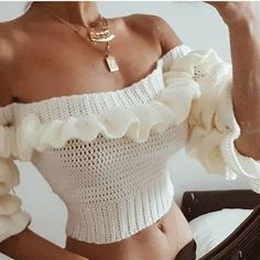 a woman wearing a white top with ruffles on the sleeves and bottom is taking a selfie