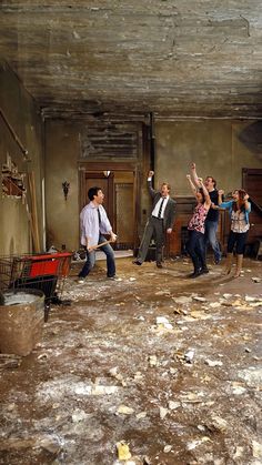 a group of people standing in an old room with debris on the floor and walls