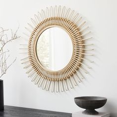 a mirror on the wall next to a bowl and vase