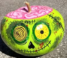 a painted pumpkin sitting on top of a cement ground