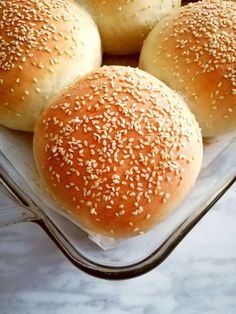 four buns with sesame seeds in a glass dish