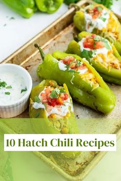 green peppers with white sauce and herbs on them, sitting on a tray next to some dips