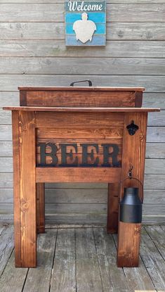 an old fashioned wooden beer dispenser sitting on a wood floor next to a welcome sign