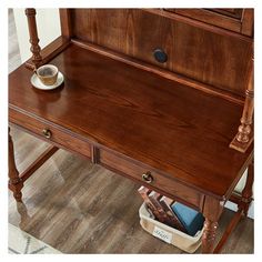 a wooden desk with two drawers and a cup on the bottom shelf next to it