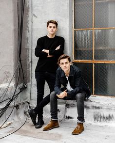 two young men sitting on steps in front of a window