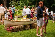 a group of people standing around a boat with food on it