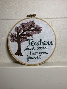 a cross - stitch hoop hanging on the wall with a quote about teachers plant seeds that grow forever