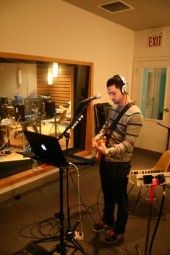 a man standing in front of a microphone with headphones on and playing an instrument