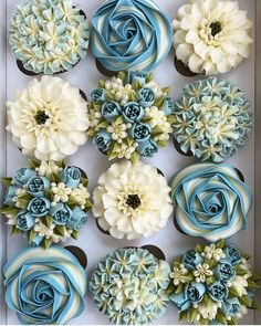 cupcakes decorated with blue and white flowers in a box