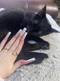 a woman laying on top of a couch next to a black cat with white nails