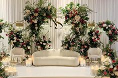 a white couch sitting on top of a table covered in flowers and candles next to chairs