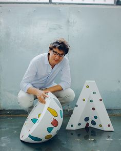 a man kneeling on the ground next to two decorative objects