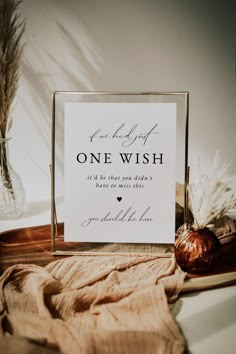 a sign sitting on top of a table next to a vase filled with dry grass