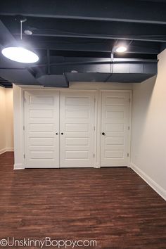 an empty room with three white doors in it's center and wood flooring on the other side