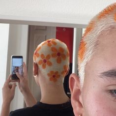 a woman taking a selfie in front of a mirror with an orange flower on her head