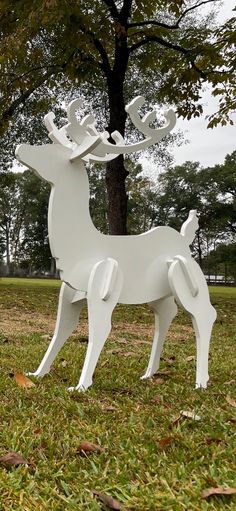 a white sculpture of a deer in the grass