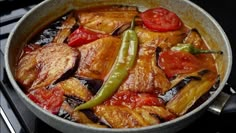 a pan filled with chicken and peppers on top of a stove next to a spatula