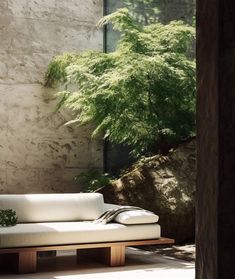 a white couch sitting in front of a stone wall next to a green planter