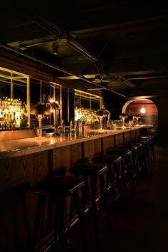 a dimly lit bar with stools in front of it