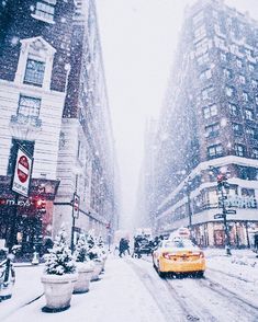 a yellow taxi cab driving down a snow covered street