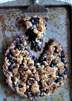 blueberry crumb pie on a baking sheet with a serving utensil next to it