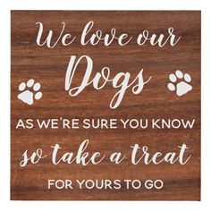 a wooden sign that says, we love our dogs as we're sure you know so take a treat for yourself to go