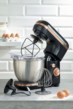 an electric mixer sitting on top of a counter next to eggs