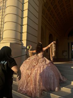 a woman in a pink dress walking up some stairs