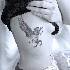 a woman with a tattoo on her stomach holding onto the side of her body and looking down