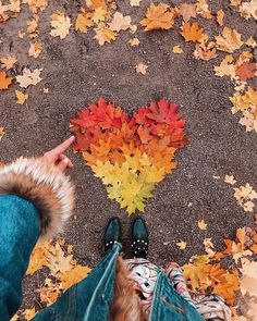 two people standing in the middle of leaves with their feet on the ground pointing at them