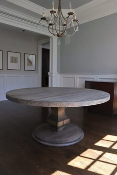 a large round dining table in the middle of a room with wood flooring and chandelier