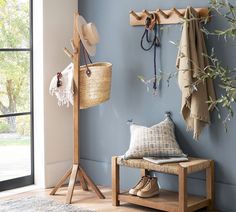 a coat rack with hats and boots hanging on it next to a bench in front of a window