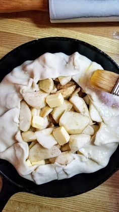 a frying pan filled with food on top of a wooden table