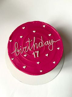 a pink birthday cake with white hearts and the words happy birthday written on it in cursive writing