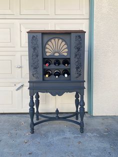 an old fashioned wine rack with bottles on it in front of a garage door,