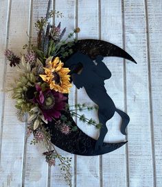 a metal moon with flowers on it sitting on top of a wooden table