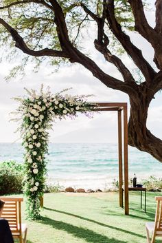 an outdoor ceremony setup with white flowers and greenery on the grass by the ocean