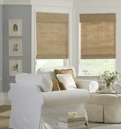 a living room filled with white furniture and lots of windows covered in shades of beige