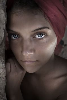 a woman with blue eyes and a red towel on her head