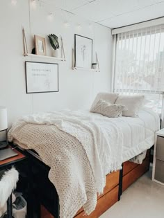 a bedroom with a bed, window and pictures on the wall