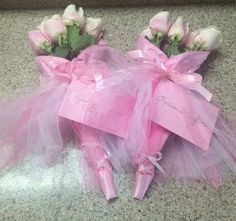 two pink roses are wrapped in tulle and tied with ribbon, sitting on the floor