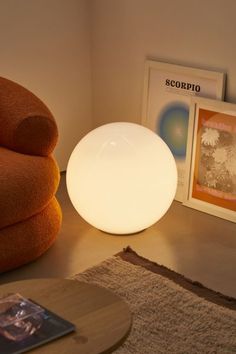 a lamp sitting on top of a wooden table next to a chair and framed pictures