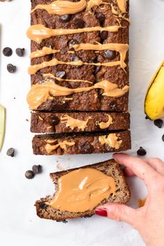 a person holding a piece of bread with peanut butter and chocolate chips on the side