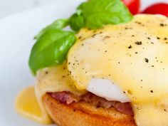 an open faced sandwich with cheese, tomato and basil on it sitting on a white plate