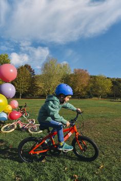 a little boy riding a bike with balloons in the background